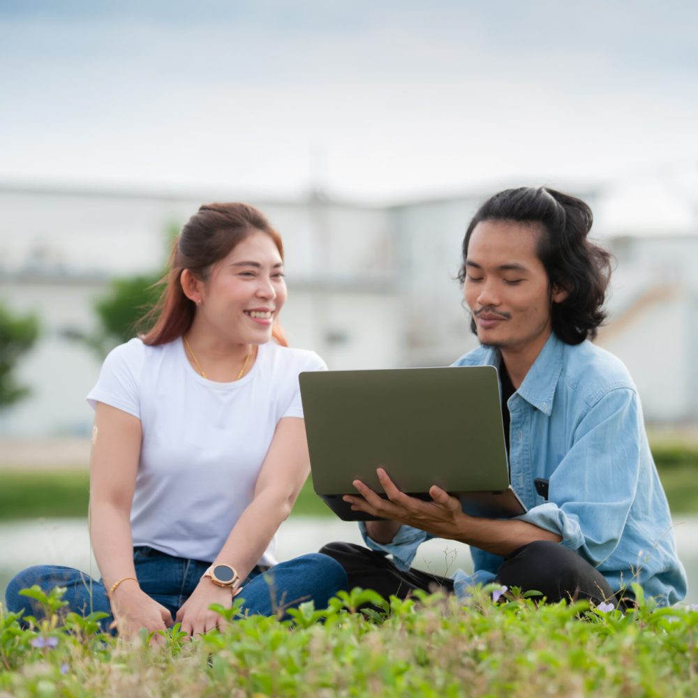 Man and woman using laptop computer sitting  outdoor