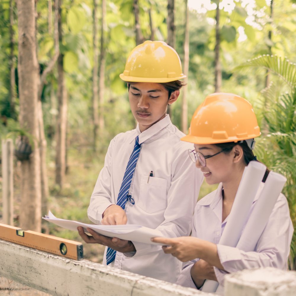 Team of male and female engineers and architects, working team, meeting, discussing construction, and inspecting the outdoor construction site work.